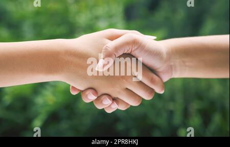 Closeup of a handshake in nature. Two diverse peoples hands greeting. Partners making an agreement about sustainability Stock Photo