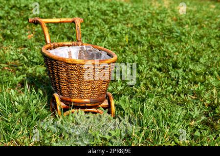 Wooden wicker brown cart in a garden on a green lawn Stock Photo