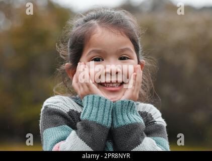 Can I go play now. an adorable little girl standing alone in the park and feeling excited. Stock Photo