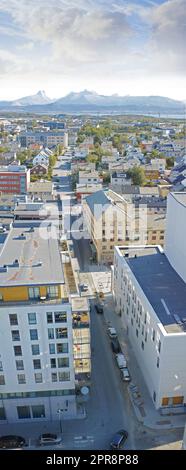 Above view of urban city streets in popular overseas travel destination in Bodo, Norway. Busy downtown centre and urban infrastructure of building architecture with scenic mountains in the background Stock Photo