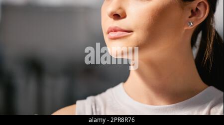 Closeup of one focused caucasian woman exercising in a gym with copyspace on the side. Face of a determined and motivated female athlete with healthy skin looking thoughtful in a fitness centre Stock Photo