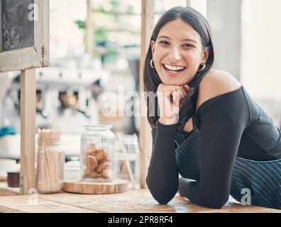 Portrait of one happy young hispanic waitress working in a store or cafe. Friendly woman and coffeeshop owner managing a successful restaurant startup Stock Photo