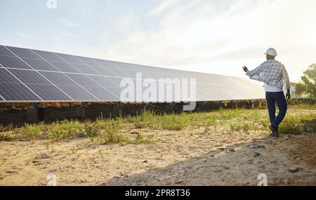 Organically grown veggies always look and taste better. a young man standing next to a solar panel on a farm. Stock Photo