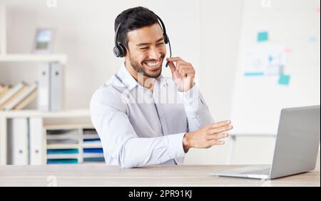 Happy businessman working in a call center. Customer service rep helping on a call. Sales agent speaking to client. IT assistant helping a customer. Telemarketing agent using headset to talk to client Stock Photo