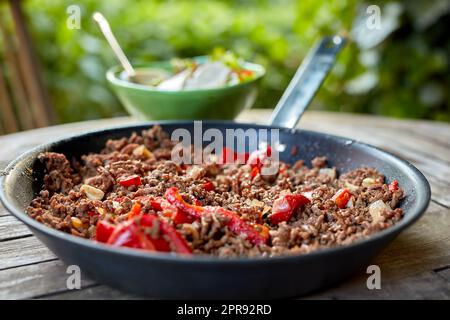 Closeup of healthy meal with minced beef meat and pepper vegetables in traditional mexican chilli dish served for lunch or dinner. Texture detail of delicious homemade food in a pan on a wooden table Stock Photo