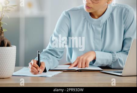 Serious finance manager writing notes, planning and checking financial paperwork reports in office. Confident boss thinking, arranging tax deadlines or calculating business profit with laptop or book Stock Photo