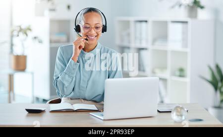 Happy call center agent calling, talking and doing online sales with a laptop and modern headset inside a company office. Smiling ecommerce consultant promoting services in telemarketing company Stock Photo