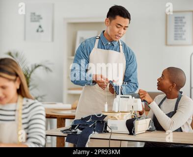 Male clothing production teacher training and giving sewing lessons. Proud entrepreneur starting a fashion and design business. Man giving side job training to adult students in the textile industry Stock Photo