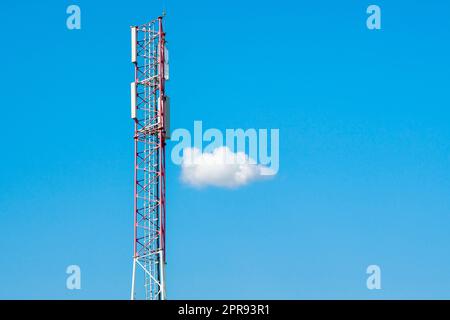 Telecommunication tower with blue sky and single white cloud Stock Photo
