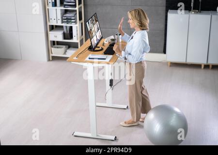 Woman Using Adjustable Height Standing Desk In Office Stock Photo