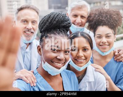 They aim to provide the best medical care. a group of doctors taking a selfie in the city. Stock Photo