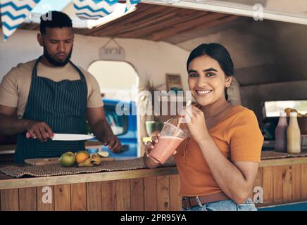 I come here every weekend. a woman buying and drinking a smoothie from a food truck. Stock Photo