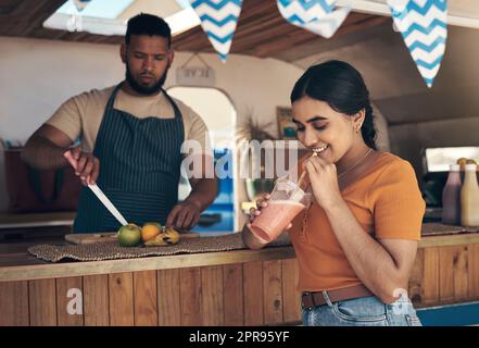 I love seeing it prepared fresh. a woman buying and drinking a smoothie from a food truck. Stock Photo