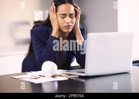 Can this day get any worse. a young businesswoman looking upset for spilling coffee over a laptop and paperwork on a table. Stock Photo