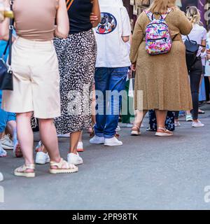 Group of young people standing in queue, rear view, summer day, selective focus Stock Photo