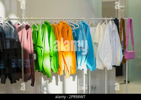 Bright youth clothes on hangers, sale in store, sunny day, selective focus Stock Photo