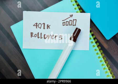 Concept of 401k Rollovers write on sticky notes isolated on Wooden Table. Stock Photo