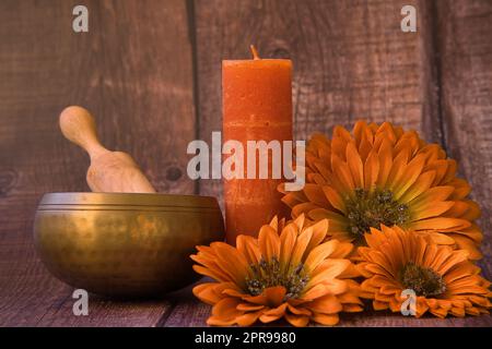 Design of spa items, candles, tibetan bowl and flowers on rustic wooden background. Stock Photo