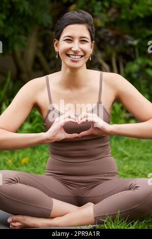 Good health is great nourishment for your body and soul. Portrait of a young woman making a heart shape with her hands while exercising outdoors. Stock Photo