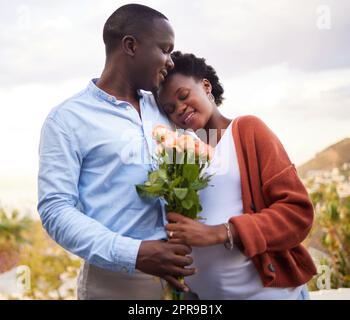 Were grateful for each other every day. a handsome young man surprising his pregnant wife with roses during a day at home. Stock Photo