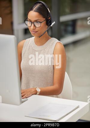 A solution to your problem is just a call away. a businesswoman using a computer while working in a call center. Stock Photo