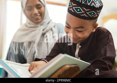 Education is the lighting of a fire. a young muslim mother and her son reading in the lounge at home. Stock Photo