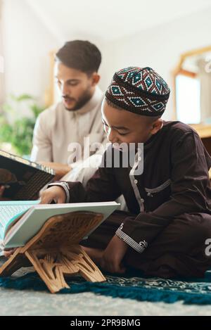 You can only provide the right conditions for learning. a young muslim man and his son reading in the lounge at home. Stock Photo