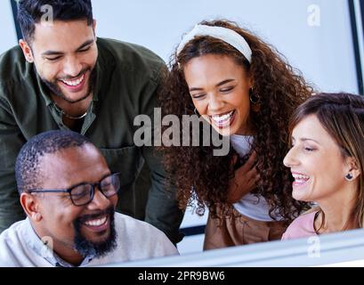 Motivated and excited to get started on their plans. a group of businesspeople working together on a computer in an office. Stock Photo