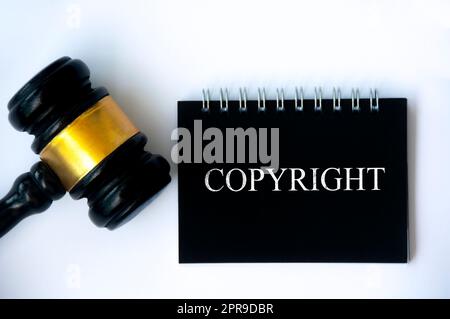 Copyright law text on black notepad and gavel on white background cover. Stock Photo