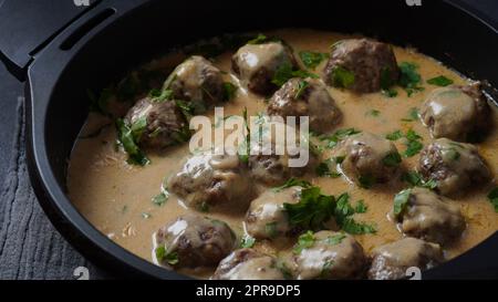 Rustic homemade Swedish meatballs in a pan with cream sauce and parsley Stock Photo