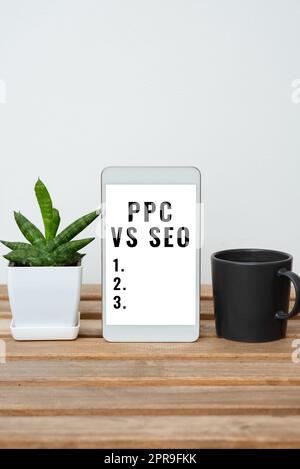 Text sign showing Ppc Vs Seo. Business overview Pay per click against Search Engine Optimization strategies Tablet With Important Information On Table With Plant And Cup Of Coffee. Stock Photo