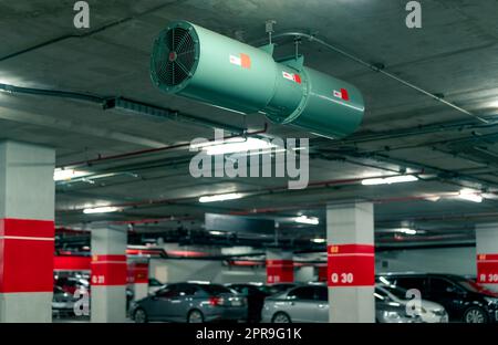 Jet fan at underground parking area. Ventilation fan in the parking lot. Air flow system. Ventilation system in underground car parking lot at commercial building. Duct fan air ventilation at mall. Stock Photo