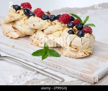 Baked cake made from whipped chicken protein and cream, decorated with fresh berries. Dessert Pavlova Stock Photo