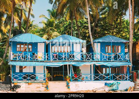 Canacona, Goa, India. Famous Painted Guest Houses On п Beach Against Background Of Tall Palm Trees In Sunny Day Stock Photo