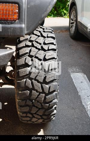 Closeup of strong indented texture of front tire of four-wheel-drive car parked on asphalt in the city Stock Photo