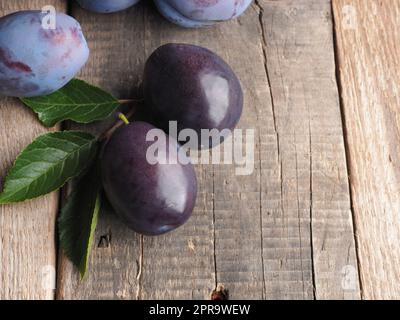Tasty organic plums on a rustic wooden kitchen table, healthy fruits Stock Photo