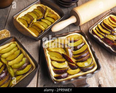 Plum cake prepared for baking on a rustic wooden kitchen table Stock Photo