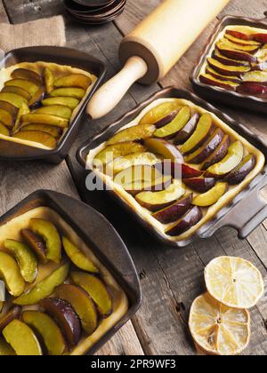 Plum cake prepared for baking on a rustic wooden kitchen table Stock Photo