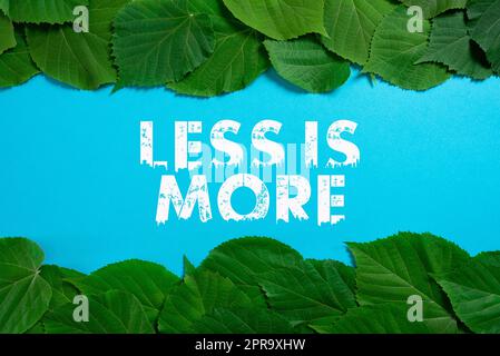 Conceptual caption Less Is More. Concept meaning Minimalist approach to artistic matter is more effective Important Informations Written On Paper Under Lot Of Leaves. Stock Photo