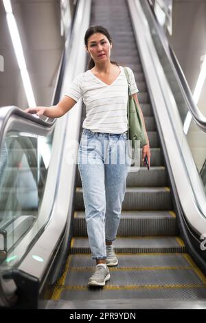 Woman going through escalator Stock Photo
