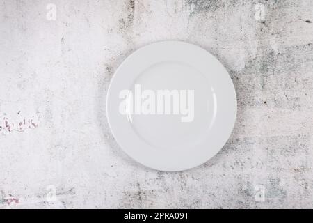 Grey stone surface with white dinner plate place setting Stock Photo