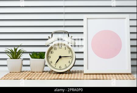 Round alarm clock stands on a white table Stock Photo