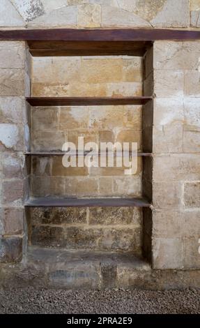 Recessed frame, Niche with wooden shelves in an old grunge stone bricks wall Stock Photo