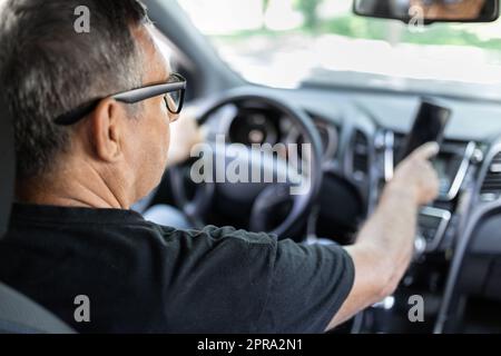 Senior behind the steering wheel using gps navigation Stock Photo