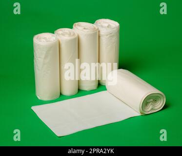 Five rolls of biodegradable eco plastic white garbage bags on green background. Stock Photo