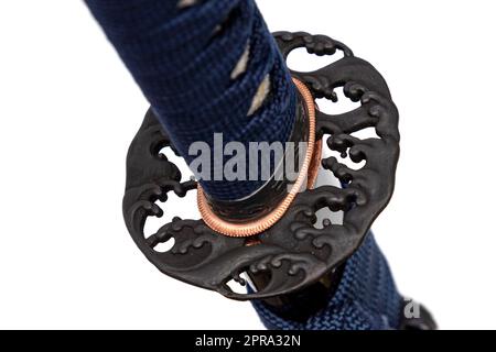Wave Design Tsuba: Japanese sword hand guard made of steel. Sword hilt and sheath wrapped with navy cord, black scabbard, isolated on white background. Stock Photo