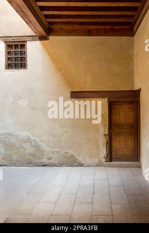 Wooden aged door and window covered with wooden grid on grunge stone wall and wood timber ceiling Stock Photo