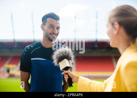 Reporter interviewing football player in a stadium Stock Photo