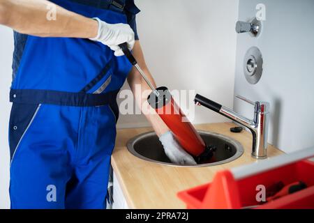 Plumber Cleaning Drain And Sink Stock Photo