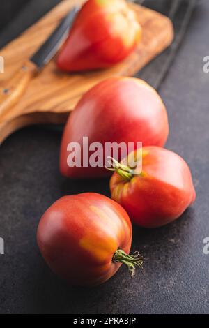 Bull heart tomatoes on black table. Stock Photo